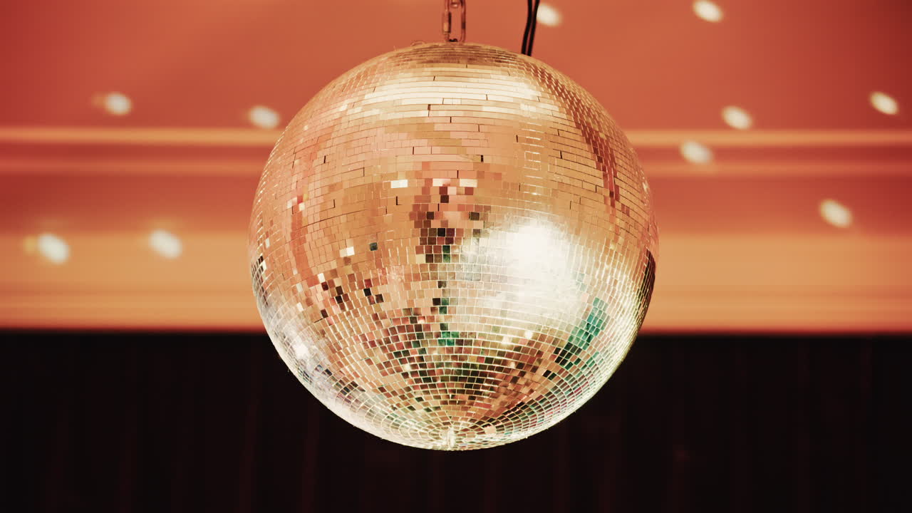 Bola de discoteca brilhante refletindo padrões de luz em um ambiente interno com iluminação quente