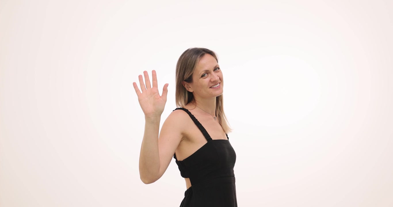 Blonde woman smiles warmly as raises hand to wave goodbye