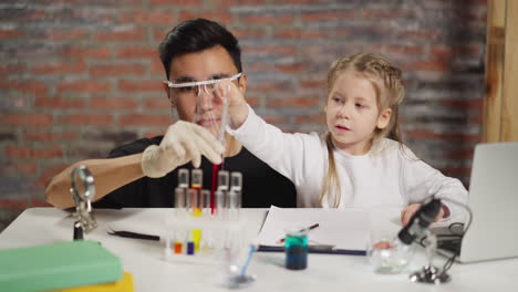 asian chemist teaches child take liquid with pipette in lab