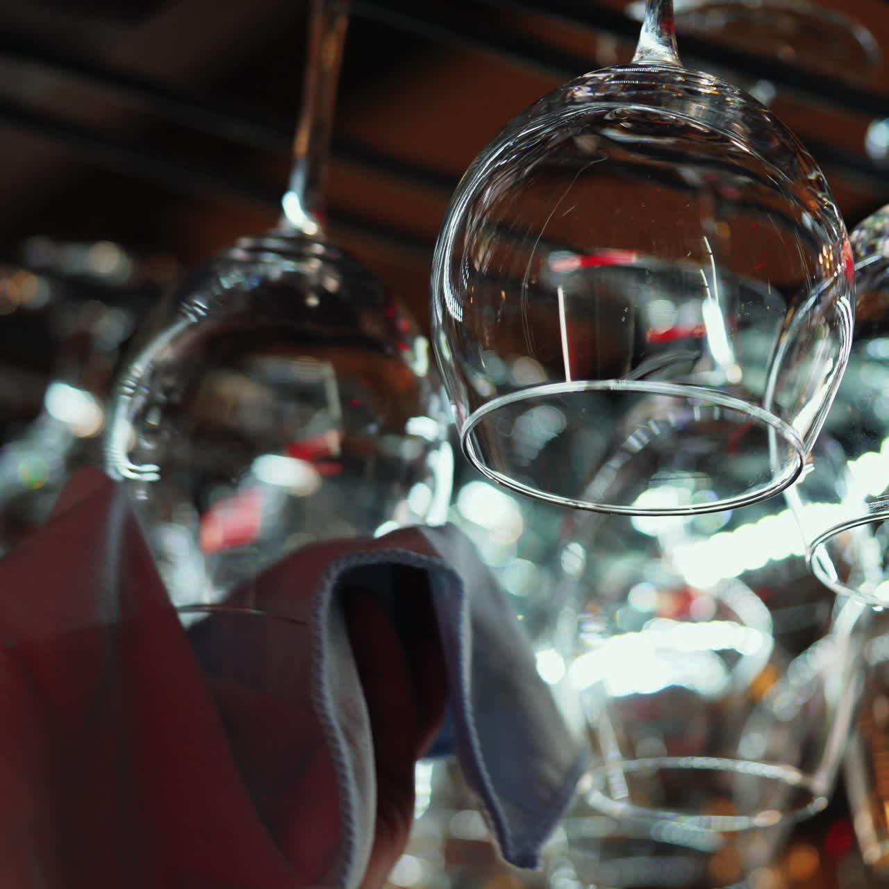 Clean wine glasses hanging upside down above a bar rack in restaurant. Bartender wipes glasses Sqare video