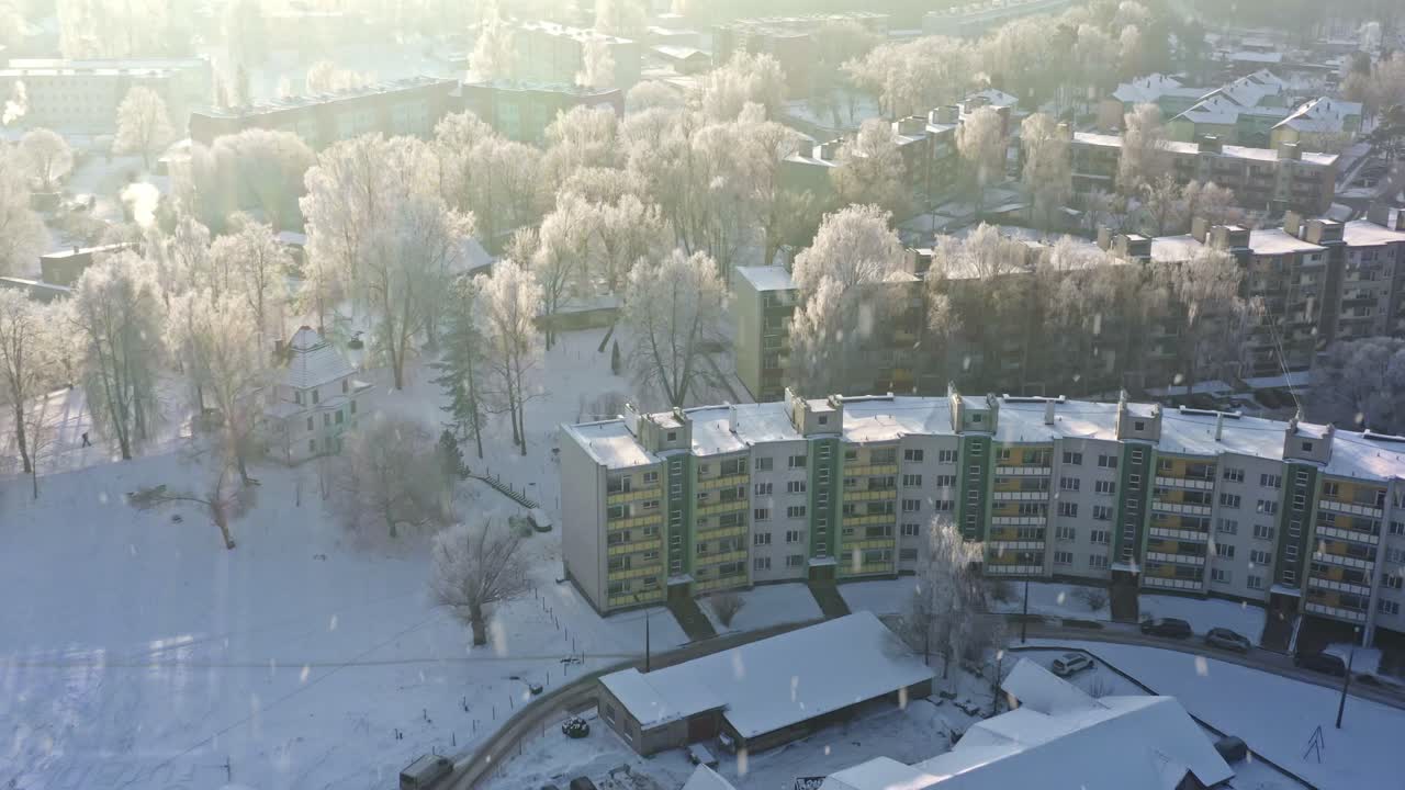 Здания жилого района, покрытые снегом, в лучах утреннего солнца и деревья в изморози зимой