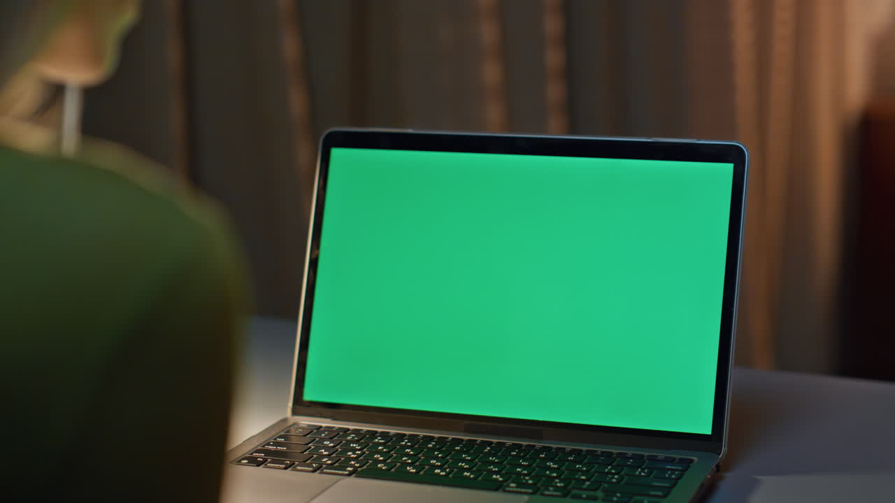 Late worker looking chroma key laptop working on project remotely close up.