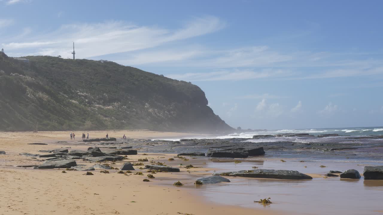 Slow motion landscape of sea waves crashing on ocean reef at sandy beach headland coastline in Forresters Beach suburbs rural town in NSW Australia travel tourism outdoors leisure nature