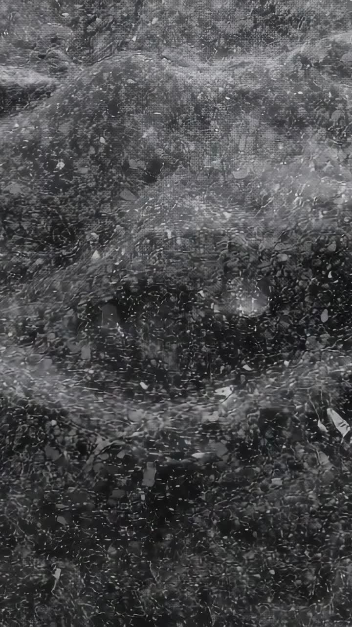 Vertical video: Rippling water making waves from central dip in closeup, showing foam and bubble
