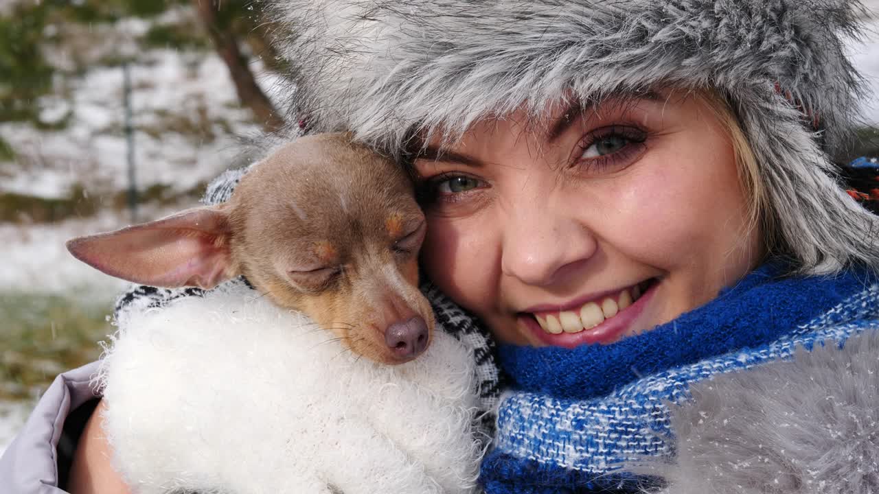 여자 는 겨울 밖 에서 작은 개 와 함께 놀고 있다