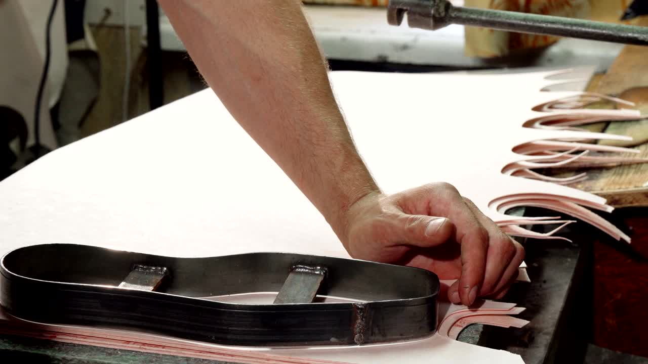 zapatero usando una máquina para cortar suelas en su taller