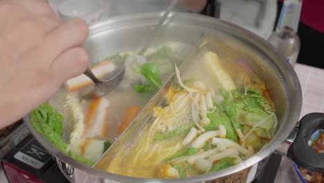 boiling shabu shabu soup in cooking pot, japanese asian food with kagosei narutomaki, fish balls, vegetables and enoki mushroom