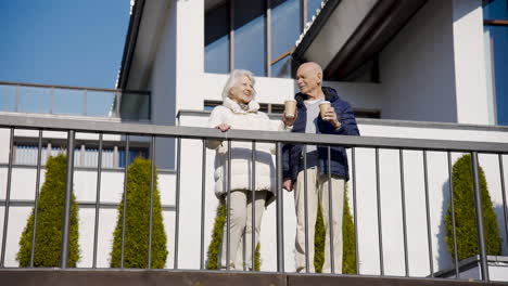 senior couple drinking coffee to go on a terrace in the park on a winter day