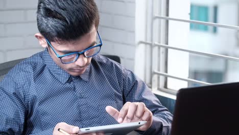 joven trabajando en una tableta y una computadora portátil
