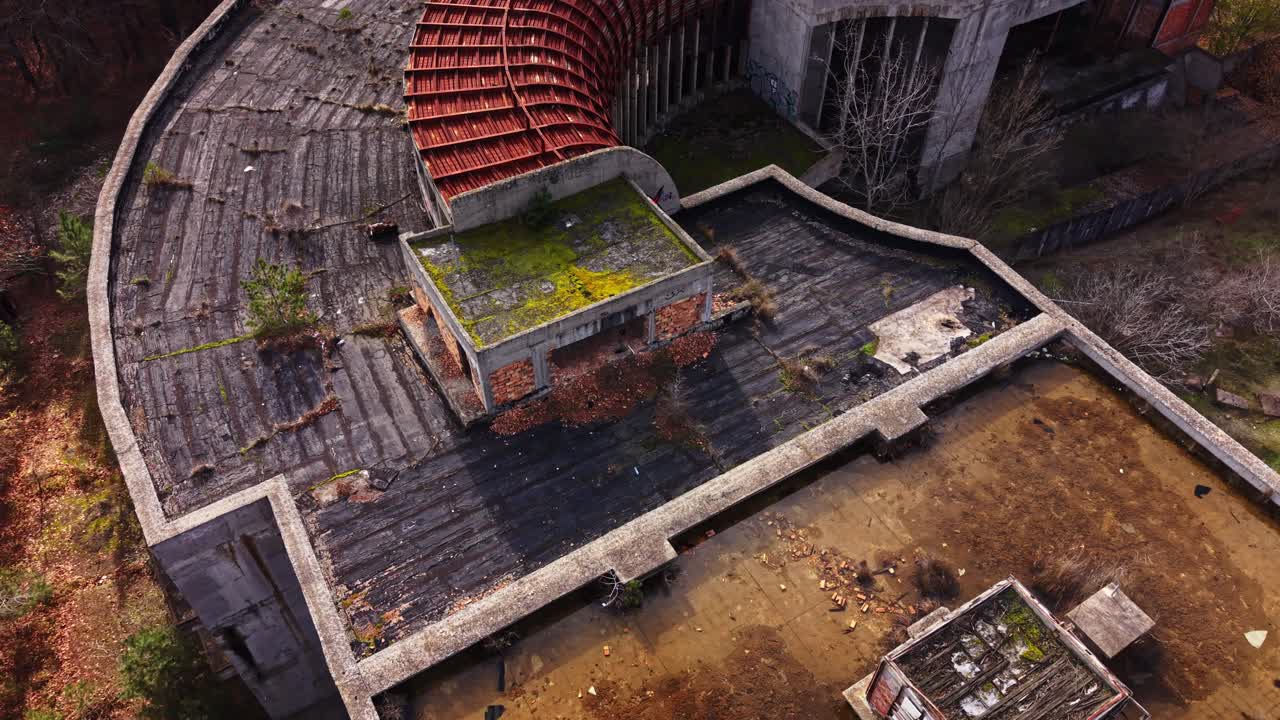 Old abandoned building with a curved roof in a forested area
