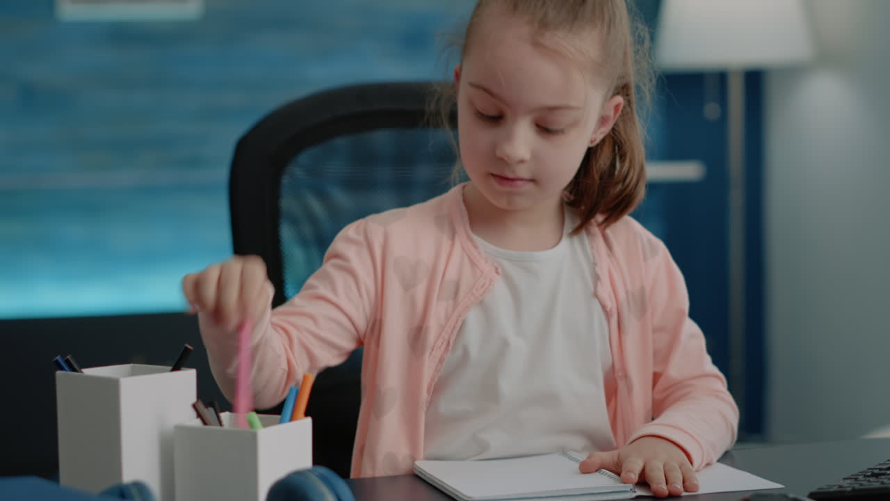 Close up of schoolgirl using pens and pencils to write on notebook