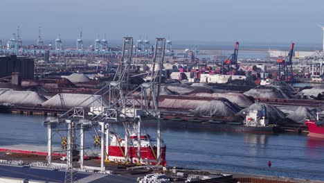 industrial container cranes and anchored freight ship in rotterdam port - aerial