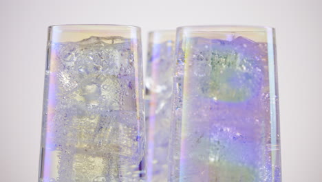 tres vasos de hielo y una bebida carbonatada clara sobre un fondo blanco de mesa giratoria