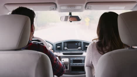 Mixed-race-couple-driving-on-vacation,-back-view