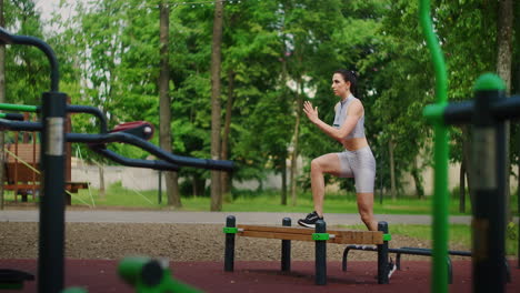 una mujer joven en un parque realiza ejercicios caminando en un banco con ropa deportiva en el verano.