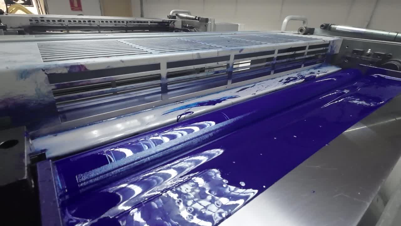 The footage highlights the cyan ink duct of an offset printing press, illustrating the intricate process of ink application. It captures the dynamic flow and distribution of rich color.