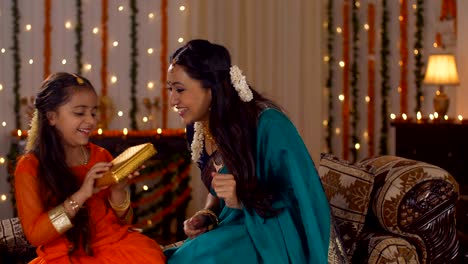 beautiful mother presenting a gift to her daughter on diwali - festival of lights