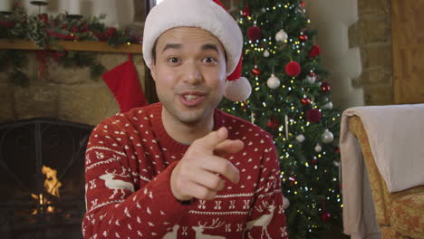 young man raising glass of champagne and talking to camera during christmas video call