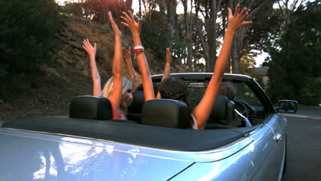 friends raising their hands in the air while man is driving
