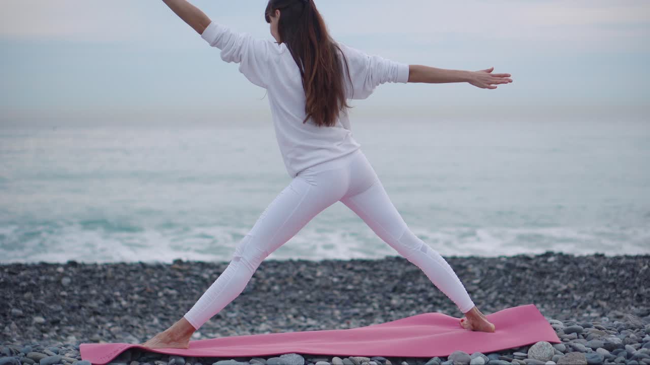 mujer practicando yoga en la playa