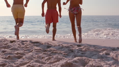 happy friends running into the sea