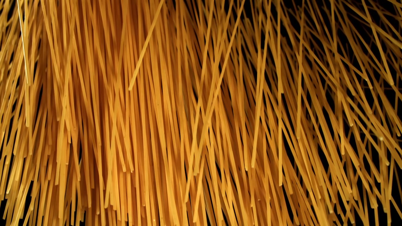 Fili di spaghetti crudi che si sollevano su sfondo nero