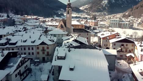 pellizzano winter scene, small mountain village church covered in snow, aerial reveal