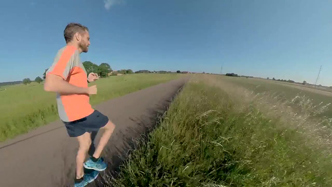 Fast approach through vegetation of a male trail runner on floodplains valley dyke bike path. Athlete endurance training run exercise outdoor sports concept.
