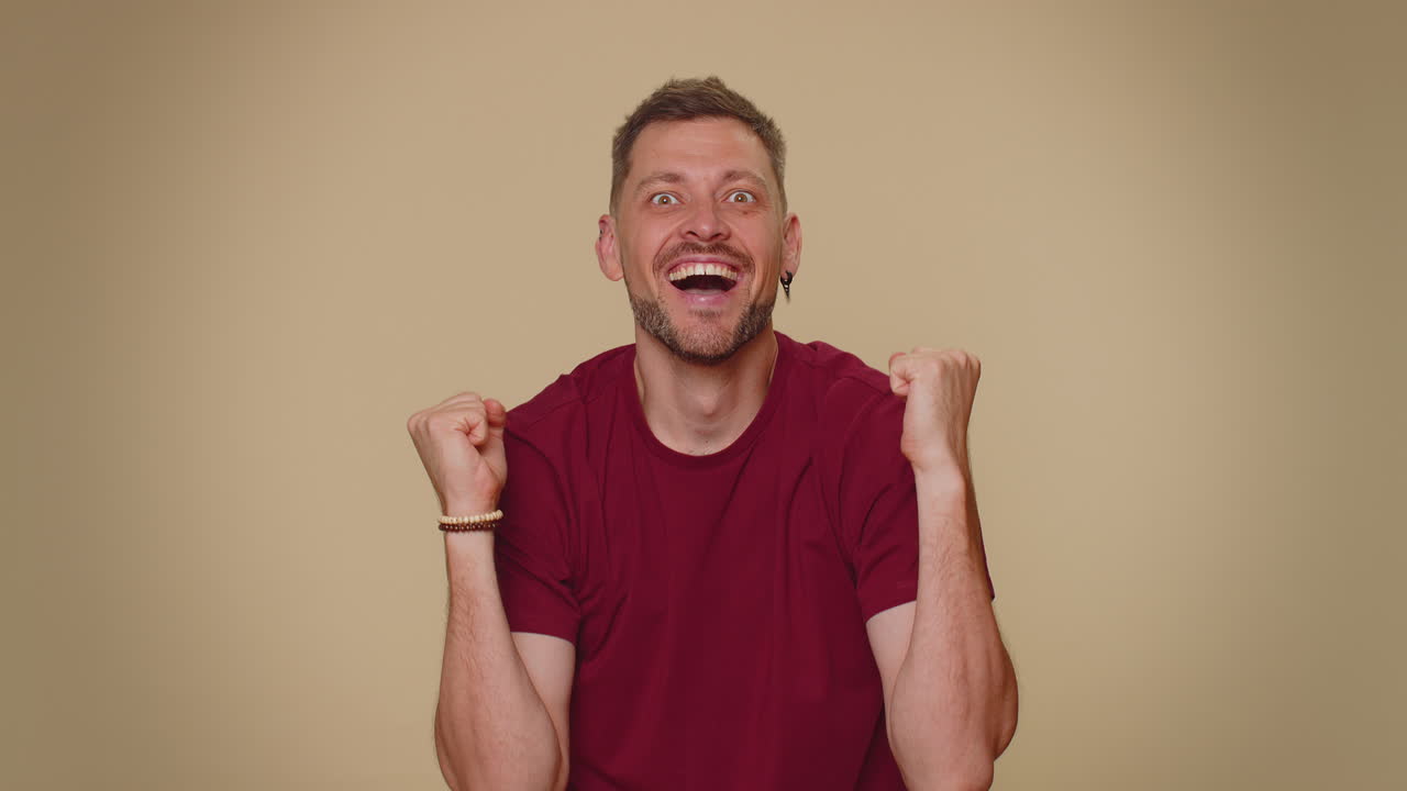 feliz joven guapo celebrar el éxito ganar gritar se regocija haciendo ganador manos gesto decir sí