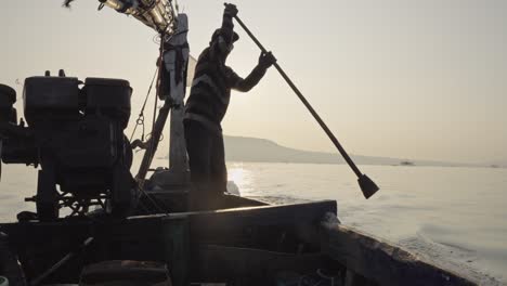 a traditional fishermen sail home against a sunrise sky, with a small island in the background