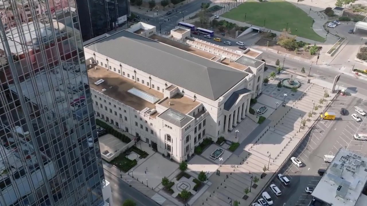 Drone-videomateriaalia, joka kiertää läheistä pilvenpiirtäjää paljastaen Nashville Symphony -rakennuksen, joka sijaitsee korkeiden rakennusten ja viheralueiden keskellä.