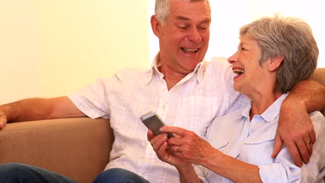 una pareja de ancianos cariñosos que usan un teléfono inteligente juntos