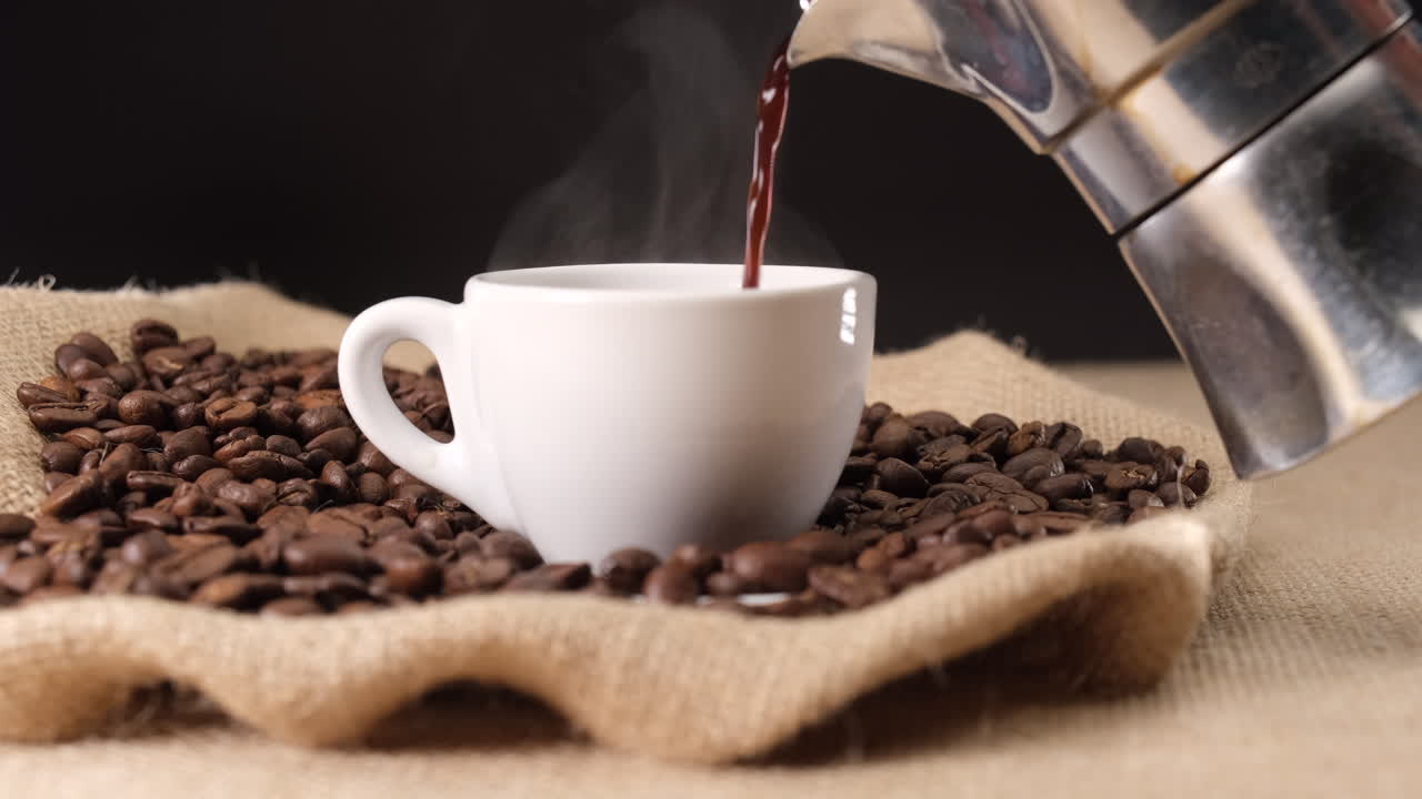 모카 커피 머신에서 뜨거운 김이 나는 커피를 컵에 붓는다