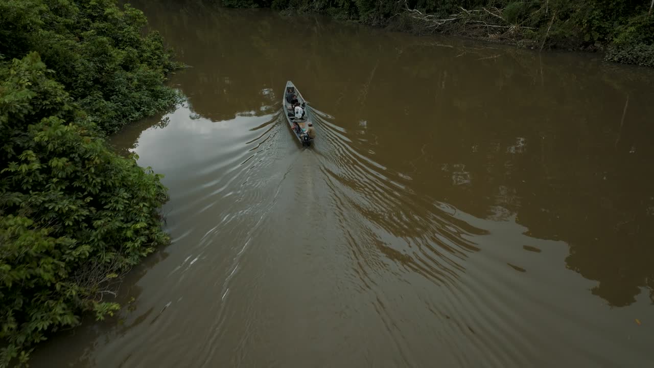Amazon Rainforest River With Indigenous Boat Sailing Across Dense Woodland