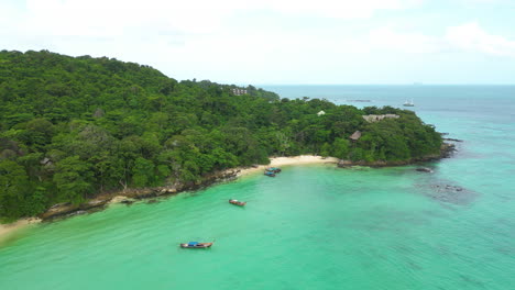 Aerial-circling-Viking-Bay,-long-tail-boats-on-coast,-Thailand