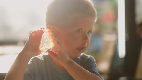 little boy puts empty glass to ear to listen sea sound