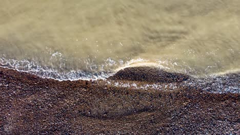 Green-looking-sea-water-waves-hitting-the-pebble-beach-on-the-Kent-coast-of-Herne-Bay-in-UK