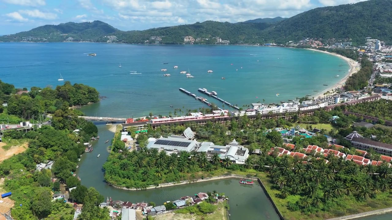 Cảnh quay từ trên cao về công trình xây dựng khu nghỉ dưỡng Phuket bên cạnh kênh đào và Vịnh Patong, drone di chuyển ngang sang phía đối diện của mặt nước