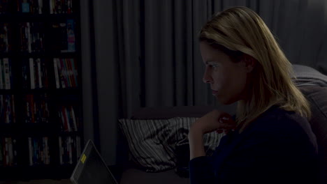 religious woman sitting on couch with laptop and looking uncomfortable to something off screen