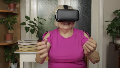 senior grandmother woman in virtual headset glasses watching 3d video in 360 vr helmet at home