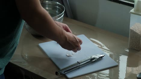 static medium shot of a home cook removing shells of hard-boiled eggs.