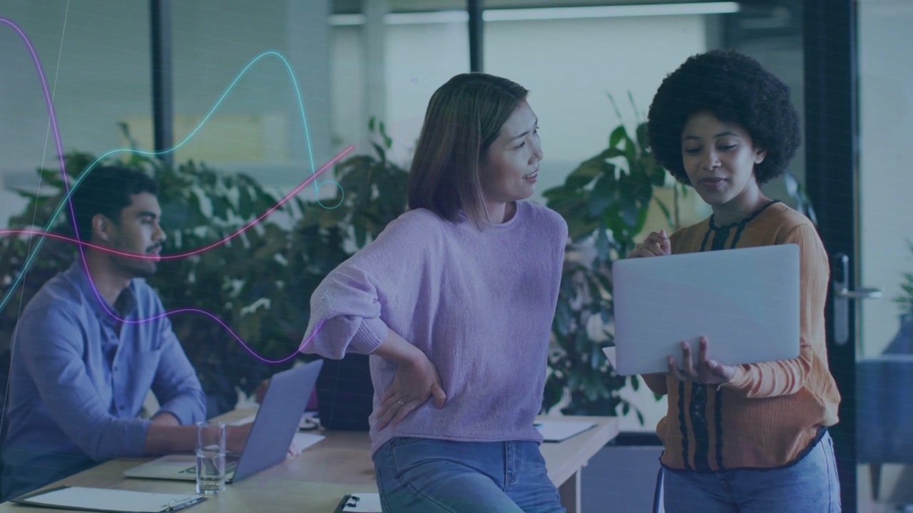Presenter tilting laptop causing graphs flowing over while business team leaning reviewing KPIs
