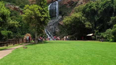 Familias-Disfrutando-De-Un-Picnic-Y-Fotos-Cerca-De-La-Cascada-En-Los-Jardines-Botánicos-Nacionales-Walter-Sisulu-En-Roodepoort,-Sudáfrica