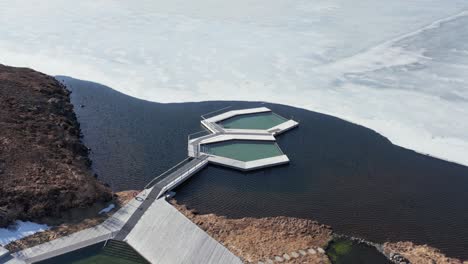 Piscinas-Infinitas-Flotantes-En-Un-Parche-Libre-De-Hielo-En-El-Lago-De-Islandia,-Antena