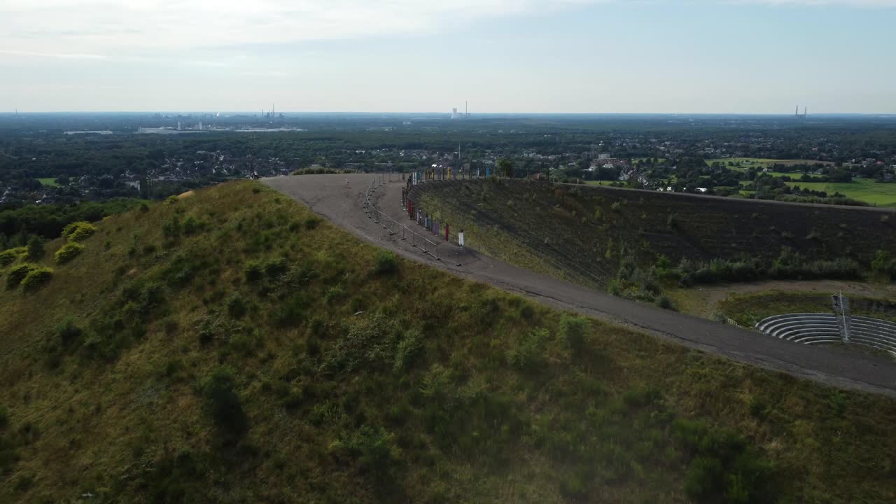 Scenic view of a hill with a road leading up, overlooking a city landscape