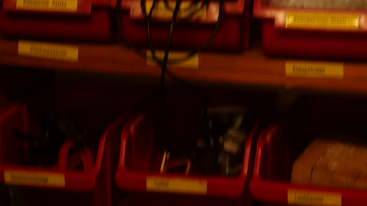 cajas rojas con componentes electrónicos y herramientas en un estante de almacenamiento