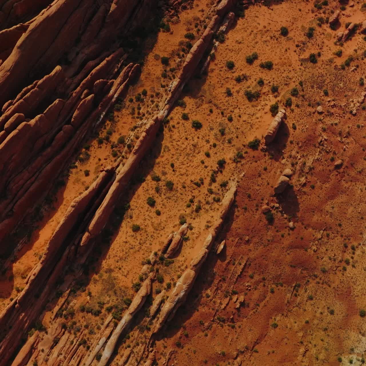 Cars driving by the road going along strangely shaped rocks. Orange desert with canyons in Utah, USA. Aerial view