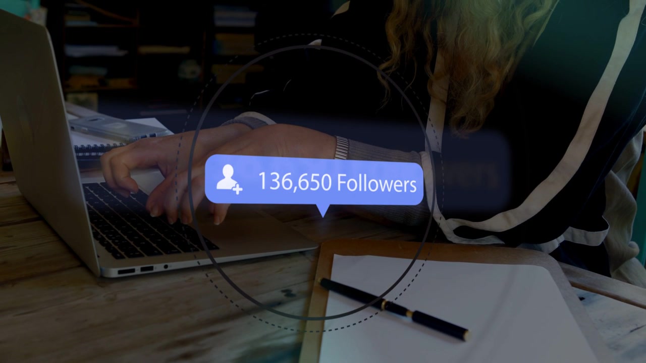 Female creator typing on laptop at desk, follower counts popping above clipboard showing growth