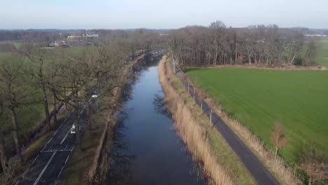 Drone-shot-of-dutch-landscape-with-canal-and-road-alongside