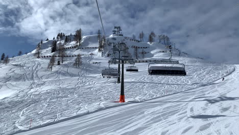 Empty-Skilifts-Moving-On-The-Ropeway-Above-Ski-Slope-In-Austrian-Alps-With-People-Skiing-On-The-During-Winter-In-Austria---POV---wide-shot